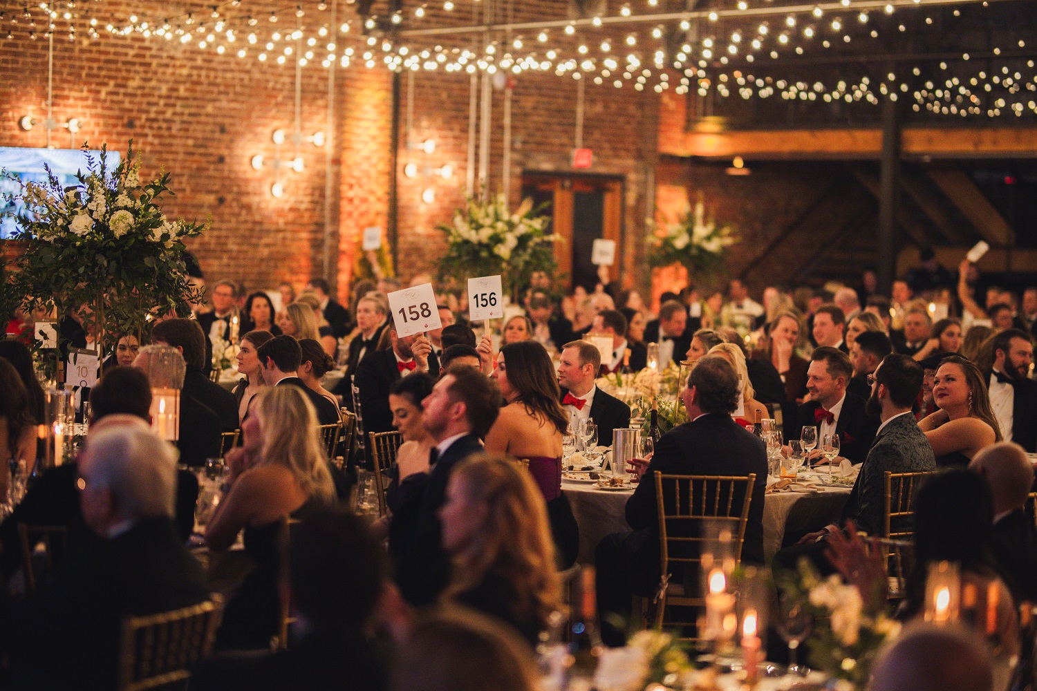 Seated guests holding up bidder paddles